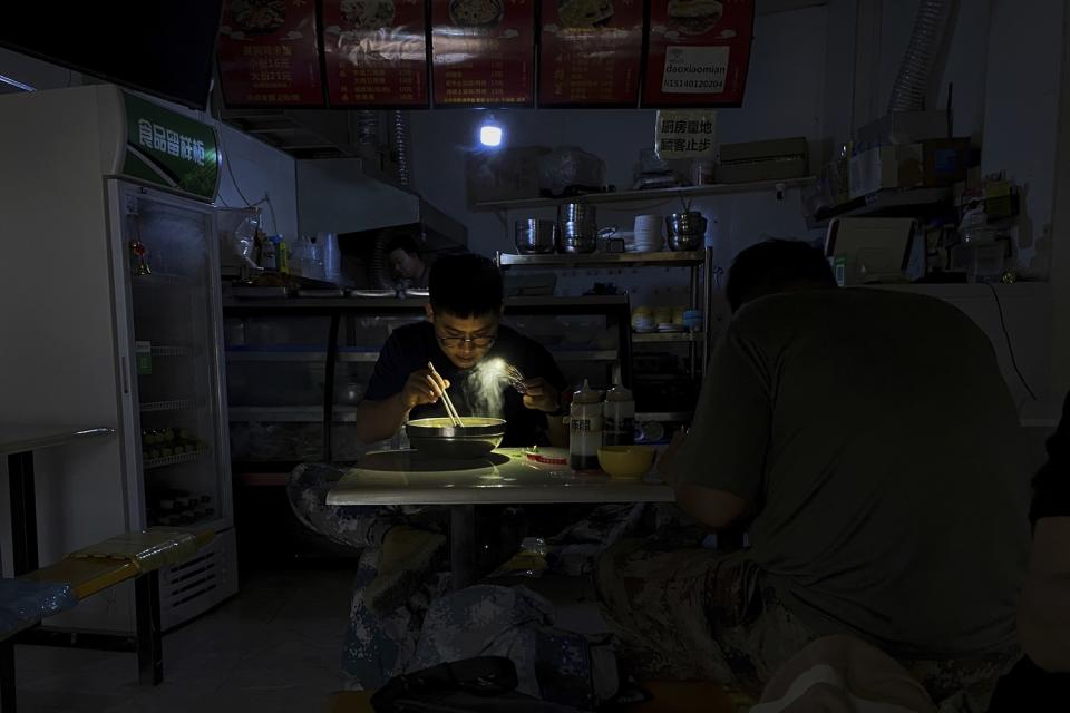 中國東北地區顧客摸黑用餐，只好利用手機的手電筒功能看清碗內食物   圖:達志影像/美聯社