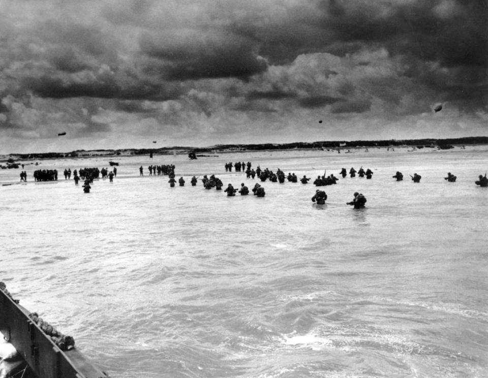 FILE - U.S. reinforcements wade through the surf as they land at Normandy in the days following the Allies', D-Day invasion of occupied France in June 1944. The D-Day invasion that helped change the course of World War II was unprecedented in scale and audacity. Veterans and world dignitaries are commemorating the 79th anniversary of the operation. (Peter J.Carroll/U.S. Coast Guard via AP, File)