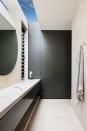 <p>Robson Rak made this narrow bathroom feel expansive with a large mirror round mirror and skylight window, which brightens up the entire room. If you don't have a ton of natural light, reflective surfaces and oversized vanity mirrors will at least make it feel a little sunnier. </p>