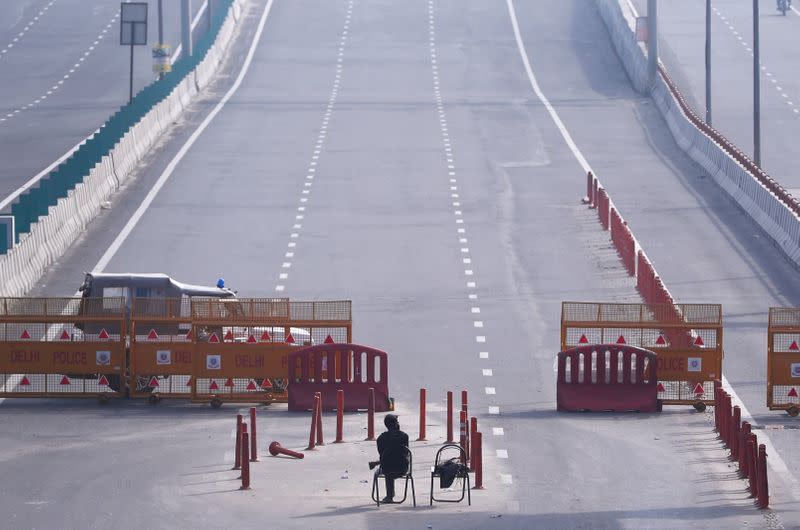 A man sits at New Delhi's border barricade during lockdown by the authorities to limit the spreading of coronavirus disease (COVID-19), in New Delhi