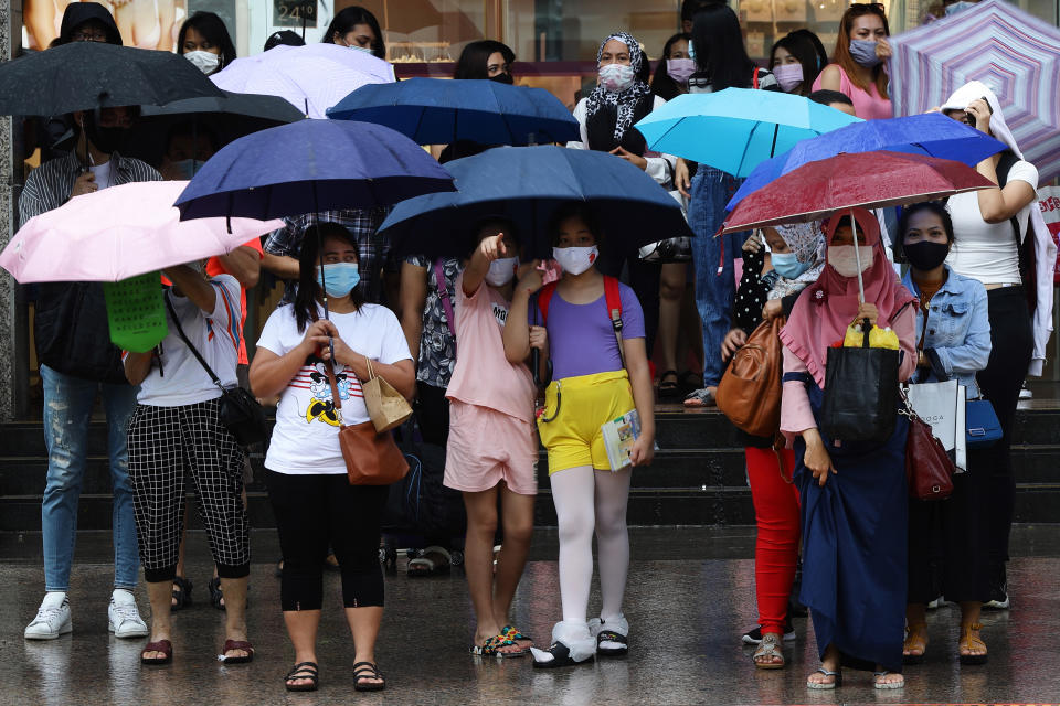 People waiting to cross a street in the rain in Singapore.