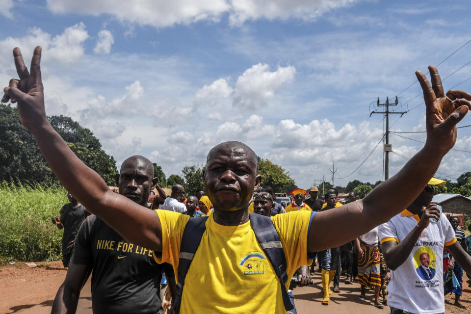 A supporter of the ruling Rally of the Guinean People (RPG) party joins others to demonstrate against the opposition Union of Democratic Forces of Guinea (UFDG) party and to block the visit of their leader, in the streets of Kankan, Guinea Sunday, Oct. 11, 2020. The stage is set for Oct. 18 presidential elections pitting incumbent President Alpha Conde, 82, who is bidding for a third term, against opposition leader Cellou Dalein Diallo, who was previously defeated by Conde in both the 2010 and 2015 elections. (AP Photo/Sadak Souici)