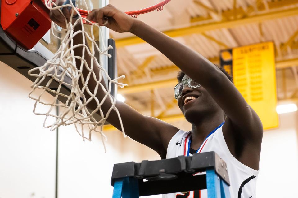 Central York sophomore Eric Tati smiles as he cuts off a piece of the net after the Panthers won YAIAA boys' basketball championship against York Suburban Friday, Feb. 16, 2024, at Red Lion Area High School. The Panthers defeated the Trojans, 63-45.