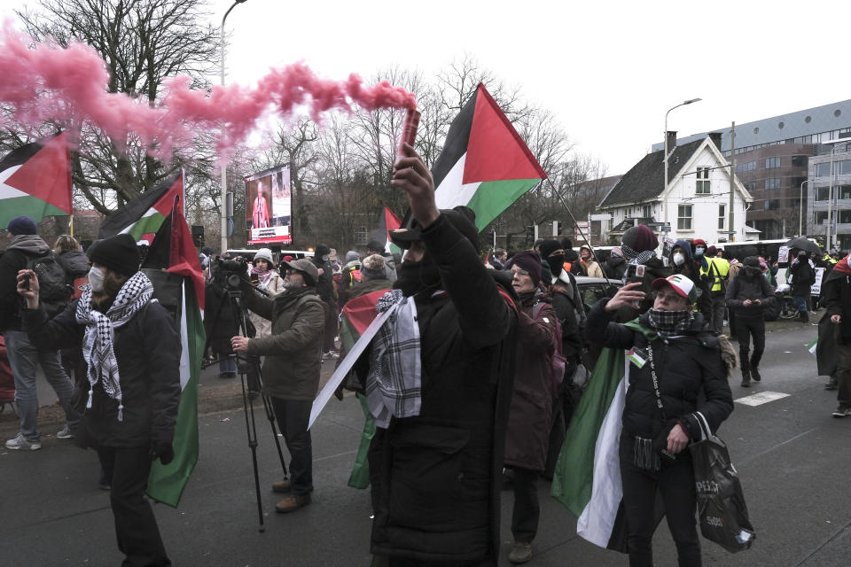 Protestors wave Palestinian flags as they march by a giant video screen projecting live hearings during a demonstration march outside the International Court of Justice in The Hague, Netherlands, Thursday, Jan. 11, 2024. The United Nations' top court opens hearings Thursday into South Africa's allegation that Israel's war with Hamas amounts to genocide against Palestinians, a claim that Israel strongly denies. (AP Photo/Patrick Post)