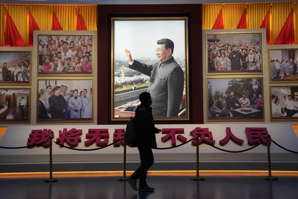 A visitor past by a photo of the Chinese President Xi Jinping and the slogan "I will have no self and live up to the People" at the Museum of the Communist Party of China here in Beijing, China, Friday, Nov. 12, 2021. Xi emerges from a party conclave this week not only more firmly ensconced in power than ever, but also with a stronger ideological and theoretical grasp on the ruling Communist Party's past, present and future. (AP Photo/Ng Han Guan)