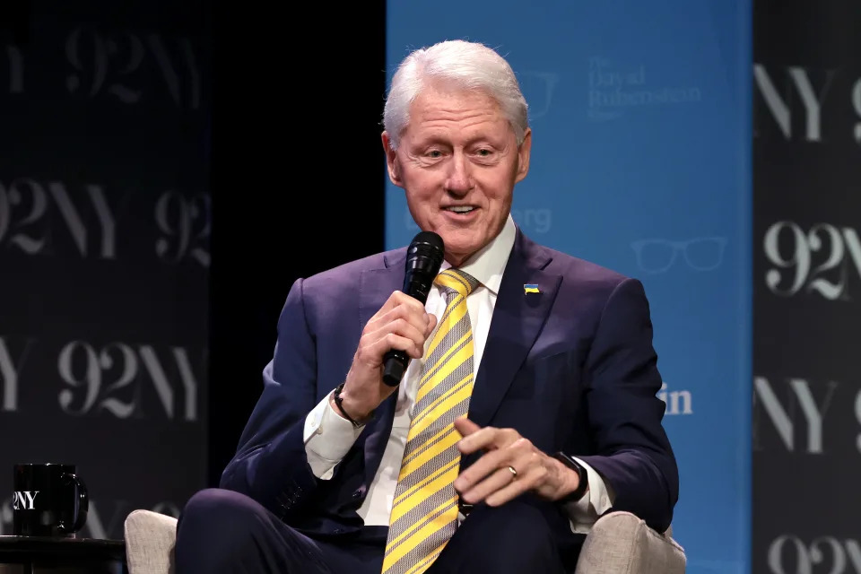 Former President Bill Clinton, seated and holding a mic, in New York City. (Jamie McCarthy/Getty Images)