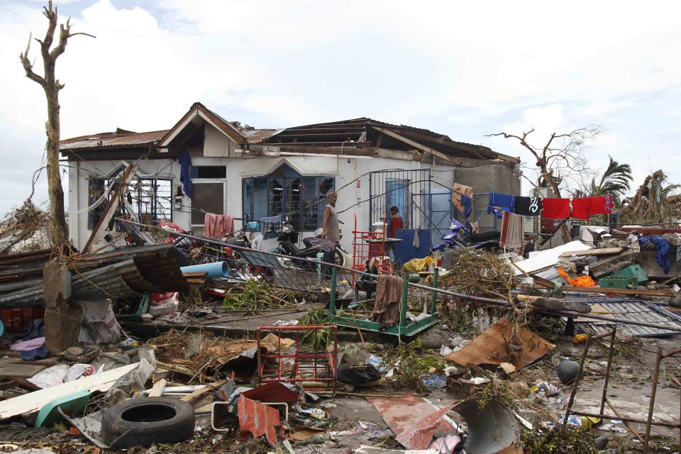 Survivors walk near their damaged house after super Typhoon Haiyan battered Tacloban city, central Philippines