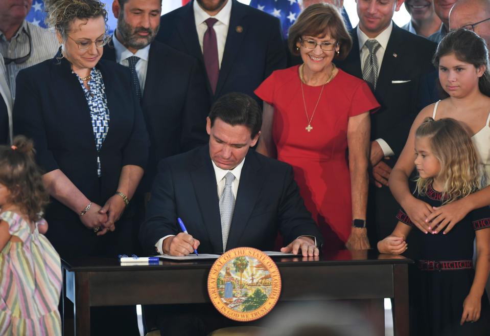 Florida Gov. Ron DeSantis signs the 2023-24 state budget at the Pelican Yacht Club in Fort Pierce on Thursday, June 15, 2023. He is flanked by Rep. Erin Grall of Vero Beach (left) and Sen. Gayle Harrell of Stuart (right).