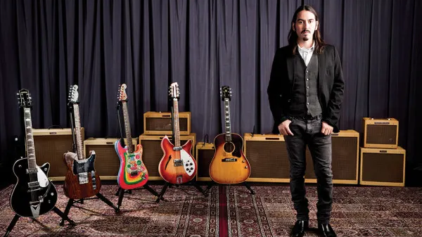 Dhani Harrison stands next to George Harrison's guitars