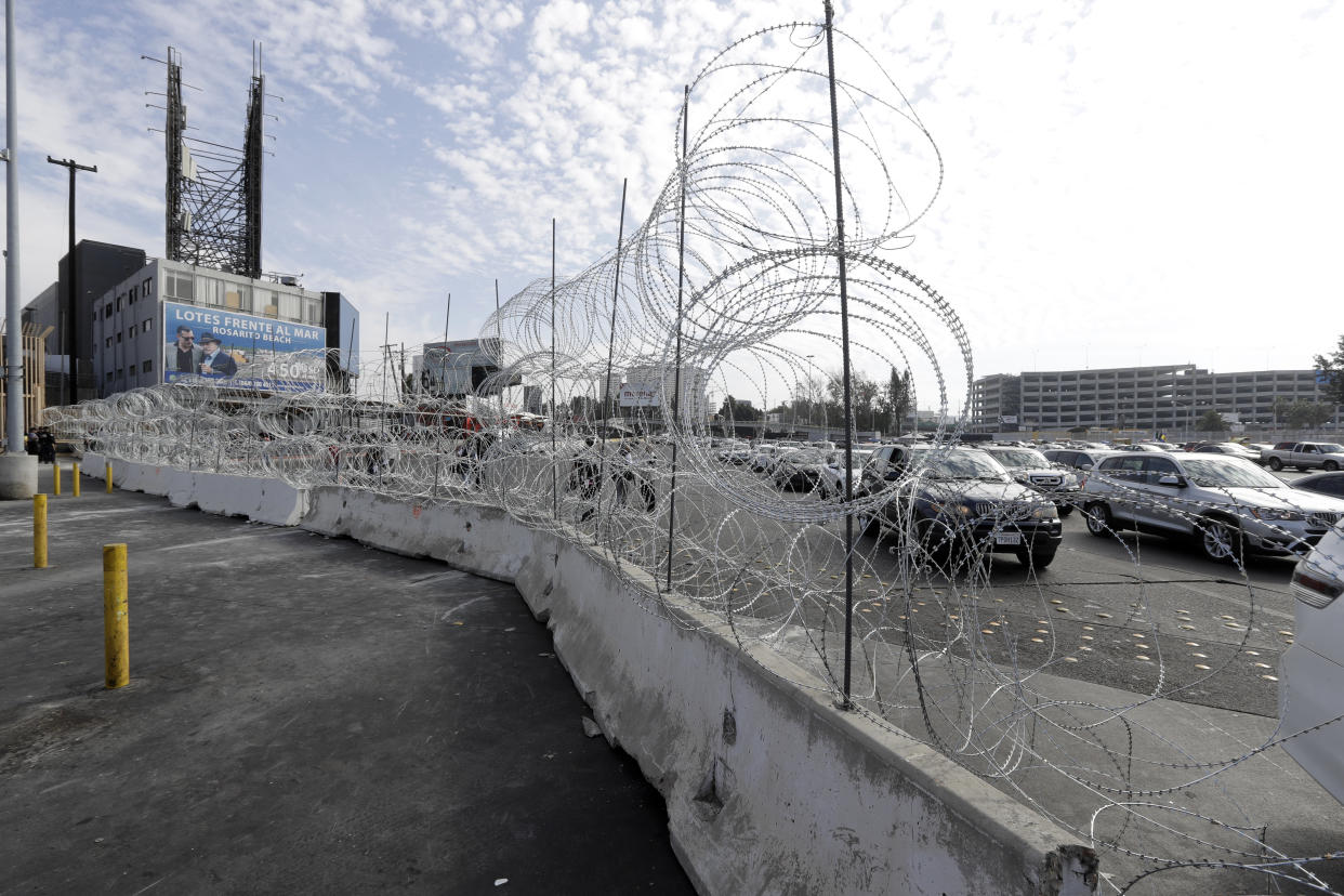 Cars lined up to cross into the United States from Tijuana, Mexico, are seen through barriers topped with concertina wire at the San Ysidro port of entry. Thieves have been taking the wire and selling it in Tijuana for home security. (Photo: Gregory Bull/ASSOCIATED PRESS)