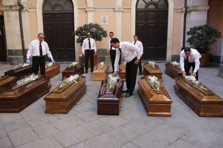 Pallbearers prepare the coffins of 13 unidentified migrants who died in the April 19, 2015 shipwreck, during an inter-faith funeral service in Catania, Italy July 7, 2015. REUTERS/Antonio Parrinello