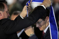 FILE - Brazil's President Jair Bolsonaro, left, honors his Environment Minister Ricardo Salles with the Order of Rio Branco, the highest diplomacy award, during a ceremony marking at the Itamaraty Palace, in Brasilia, Brazil, Oct. 22, 2020. In Bolsonaro’s cabinet, a medal has practically come with the job. The nation’s three medals regarded as most prestigious are the Order of Defense Merit, Order of Rio Branco and the Medal of Victory, and Bolsonaro has awarded more than three-quarters of current or former ministers at least one. (AP Photo/Eraldo Peres, File)