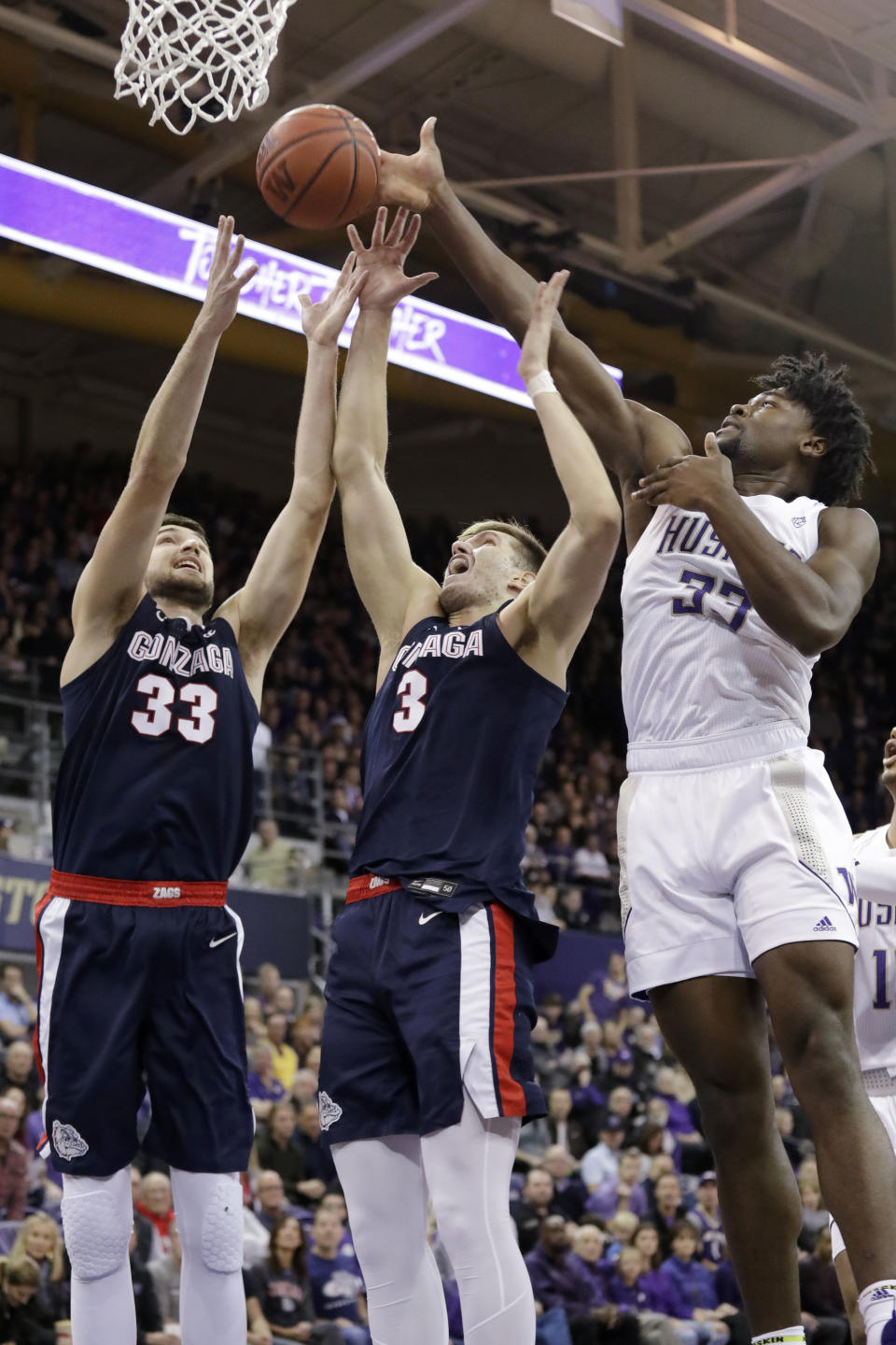 Gonzaga's Killian Tillie (33) and Filip Petrusev (3) reach for a rebound with Washington's Isaiah Stewart (33) in the first half of an NCAA college basketball game Sunday, Dec. 8, 2019, in Seattle. (AP Photo/Elaine Thompson)