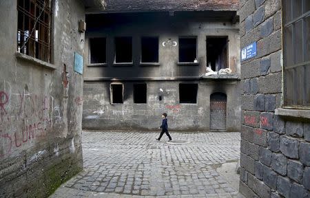 A boy walks past by a damaged building in Sur district, which is partially under curfew, in the Kurdish-dominated southeastern city of Diyarbakir, Turkey February 19, 2016. REUTERS/Sertac Kayar