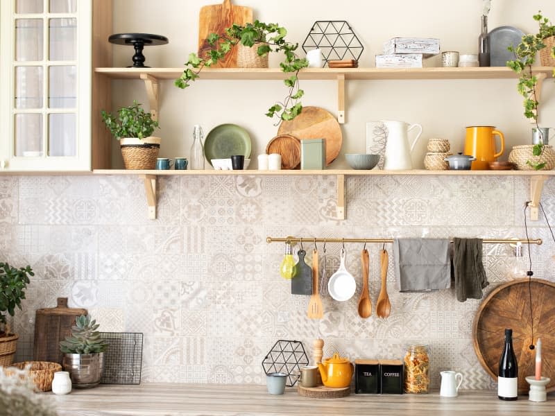 Stylish scandi cuisine interior decor. Ceramic plates, dishes, utensils and cozy decor on wooden shelfs. Kitchen wooden shelves with various ceramic jars and cookware. Open shelves in the kitchen.