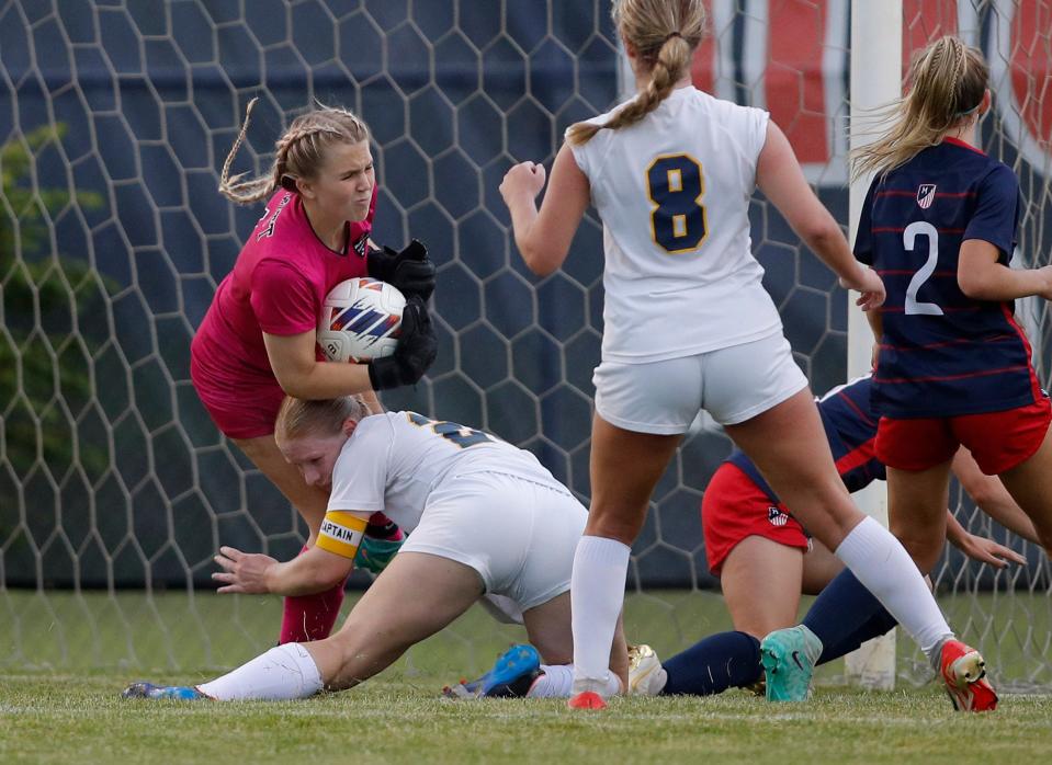 DeWitt's Sarah Reynolds, bottom left, collides with goalkeeper Madison McDonald, left, as they defend against a Mason attack during the Gold Cup final game, Thursday, May 16, 2024, at Mason High School. Mason won in a 2-1 shootout after a scoreless tie in regulation.