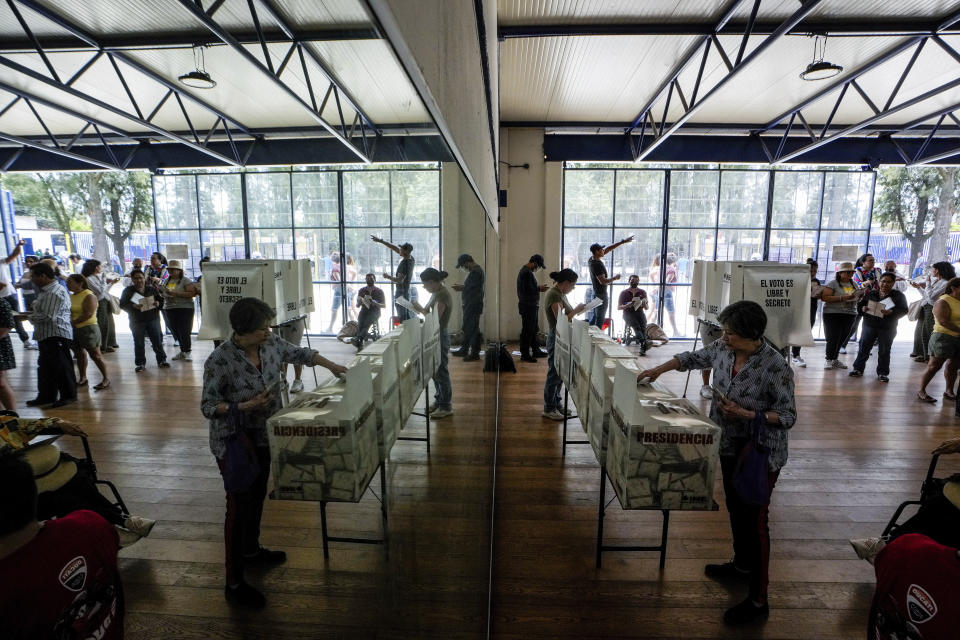 Una votante, reflejada en un espejo, vota en las elecciones generales en Ciudad de México, el domingo 2 de junio de 2024. (AP Foto/Matías Delacroix)