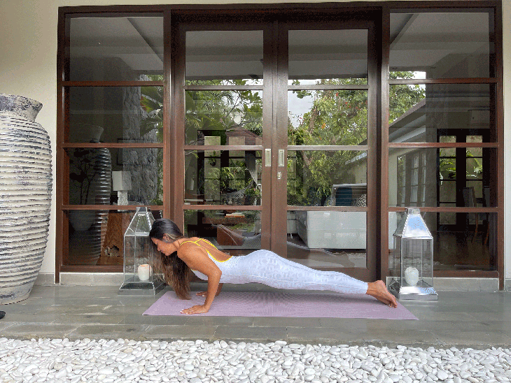Woman in a low push or or Chaturanga on a yoga mat while practicing a 10-minute yoga flow