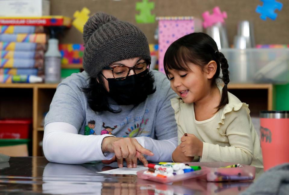 Norma Zapien, La Escuelita program coordinator, works with Aryah Rubio on an activity matching animals to their homes.