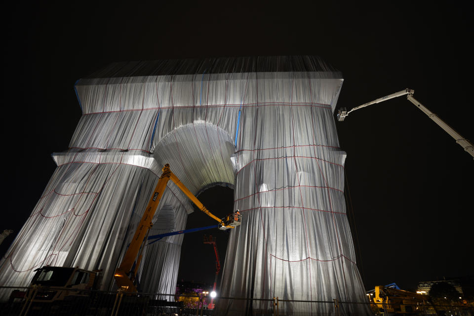 Workers wrap the Arc de Triomphe monument, Wednesday, Sept. 15, 2021 in Paris. The "L'Arc de Triomphe, Wrapped" project by late artist Christo and Jeanne-Claude will be on view from, Sept. 18 to Oct. 3. The famed Paris monument will be wrapped in 25,000 square meters of fabric in silvery blue, and with 3,000 meters of red rope. (AP Photo/Francois Mori)