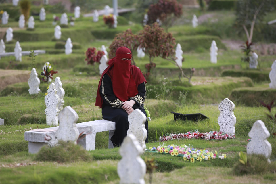 A Muslim woman sits near the grave of a relative at a cemetery reserved for those who died of COVID-19, in Medan, North Sumatra, Indonesia, Thursday, March 31, 2022. Prior to the holy fasting month of Ramadan that is expected to begin on Sunday, Muslims followed local tradition to visit cemeteries to pray for their deceased loved ones. (AP Photo/Binsar Bakkara)