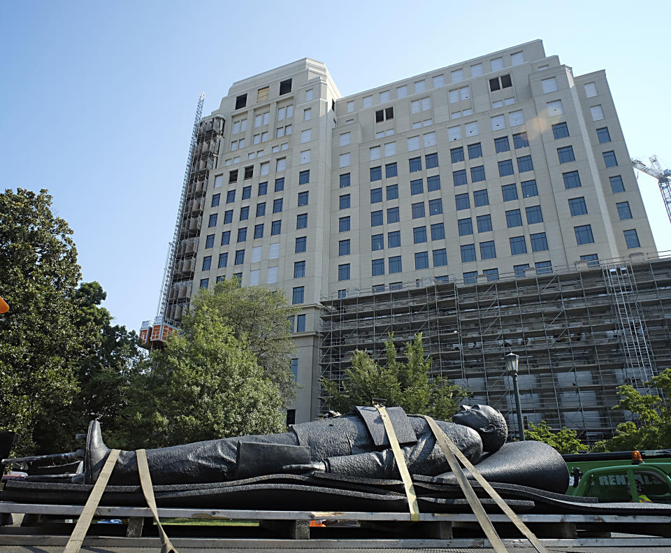 The statue of Harry F. Byrd, Sr., former Virginia Governor and U. S. Senator, lies on a flatbed truck in front of the new General Assembly Building under construction after it was removed from the pedestal in Capitol Square in Richmond, Va. Wednesday, July 7, 2021. The General Assembly approved the removal during the last session. (Bob Brown/Richmond Times-Dispatch via AP)