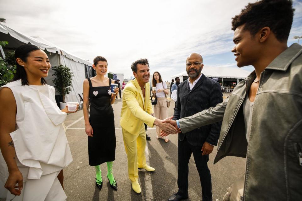 Actors and directors greet each other outdoors at an awards show.