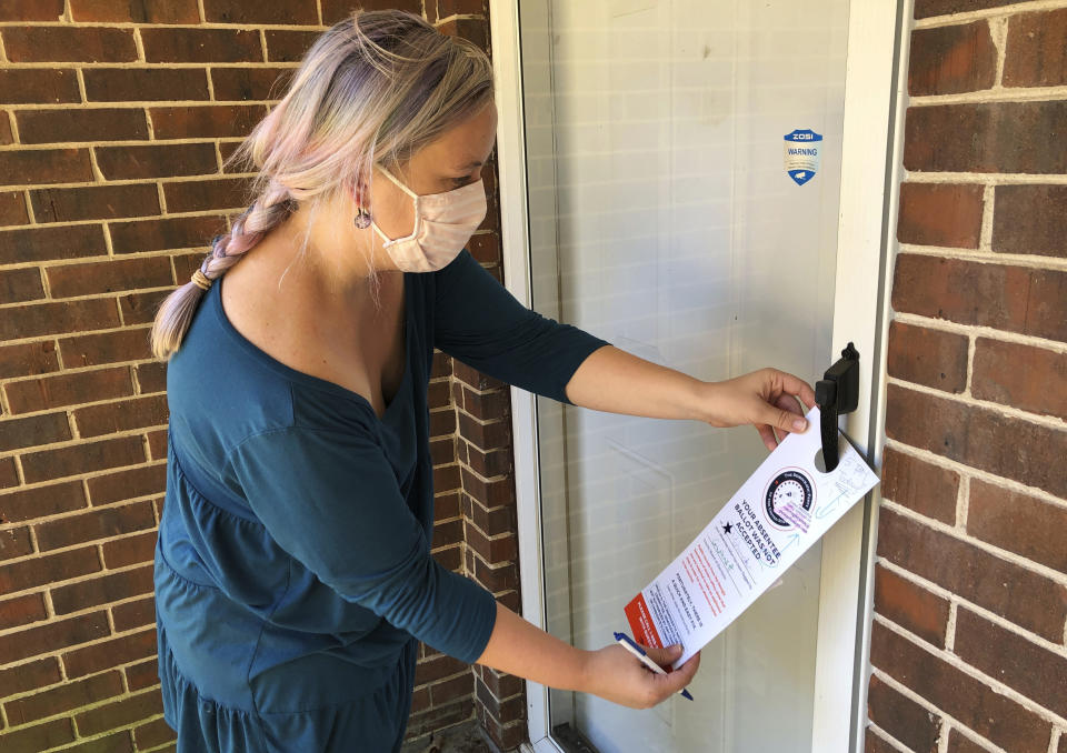 Christin Clatterbuck leaves an affidavit and information about fixing absentee ballots on the door of a home in Stone Mountain, Ga., Friday, Nov. 6, 2020. (AP Photo/Sudhin Thanawala)