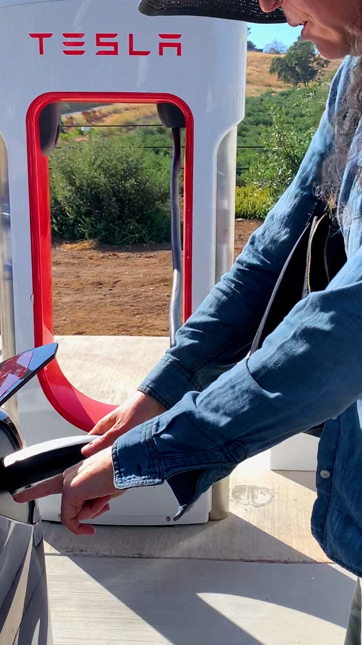 Woman charging Tesla 3 at a Supercharger.