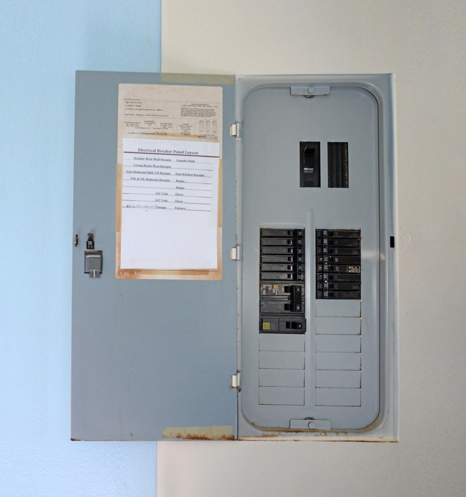 An open electrical breaker panel with various switches and a list of circuits taped inside the door