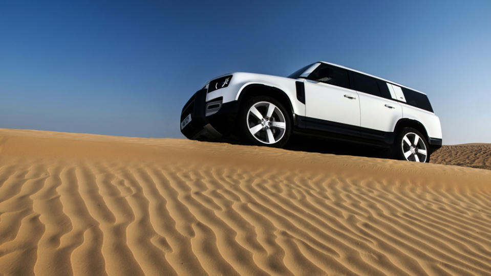 The 2023 Land Rover Defender 130, in Fuji White, atop a dune in Dubai.