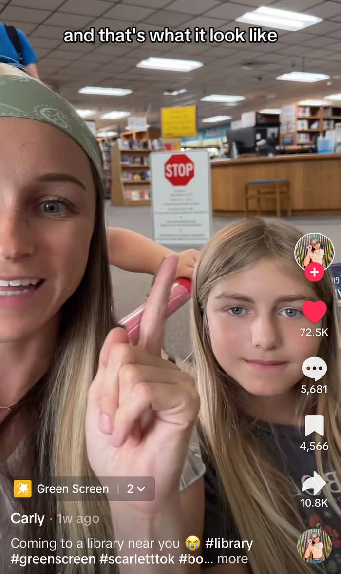 Carly and a young girl at the Idaho library, with a library sign in the background. Carly is pointing up