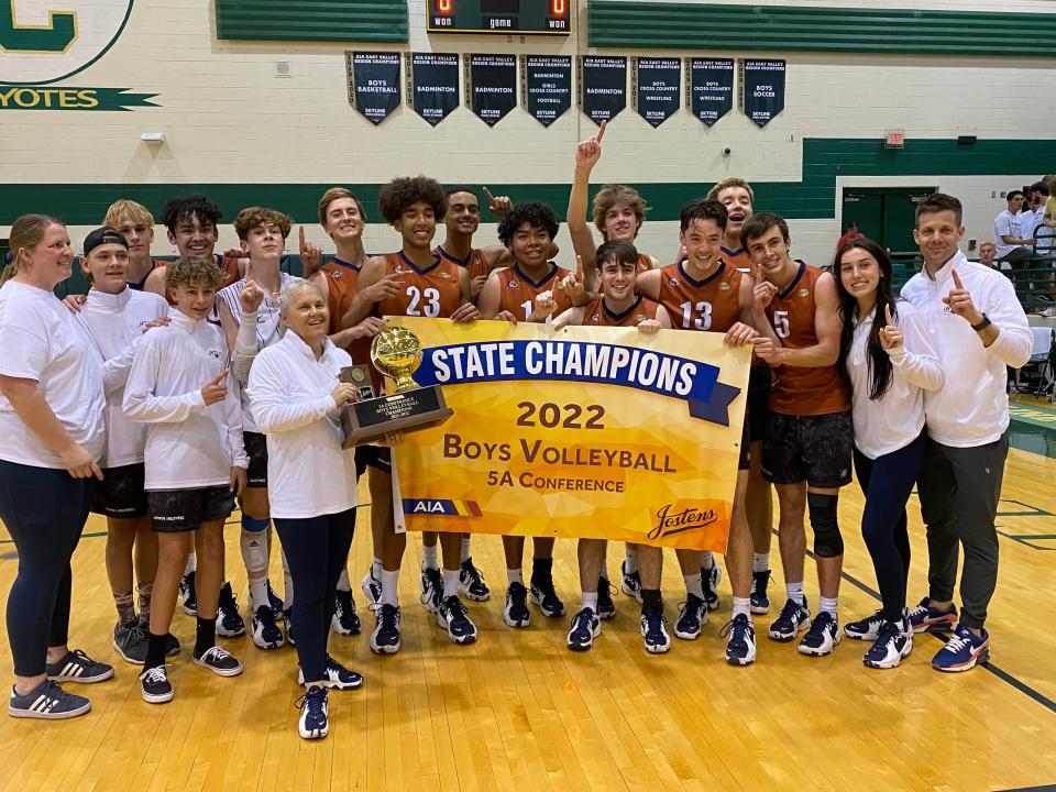 Cienega's boys volleyball team holds the 2022 state championship banner.