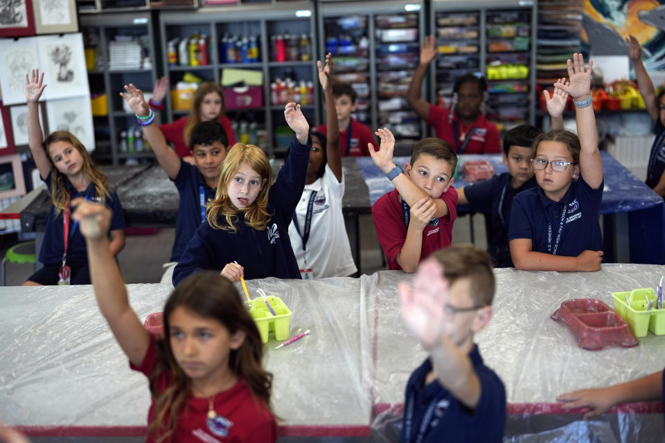 Students raise their hands in Lindsey Wuest's Science As Art class at A.D. Henderson School in Boca Raton, Fla., Tuesday, April 16, 2024. When teachers at the K-8 public school, one of the top-performing schools in Florida, are asked how they succeed, one answer is universal: They have autonomy. (AP Photo/Rebecca Blackwell)