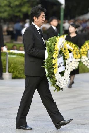 Japanese Prime Minister Shinzo Abe carries a wreath to the cenotaph for the victims of the 1945 atomic bombing at Peace Memorial Park in Hiroshima, western Japan, in this photo taken by Kyodo August 6, 2016. Mandatory credit Kyodo/via REUTERS