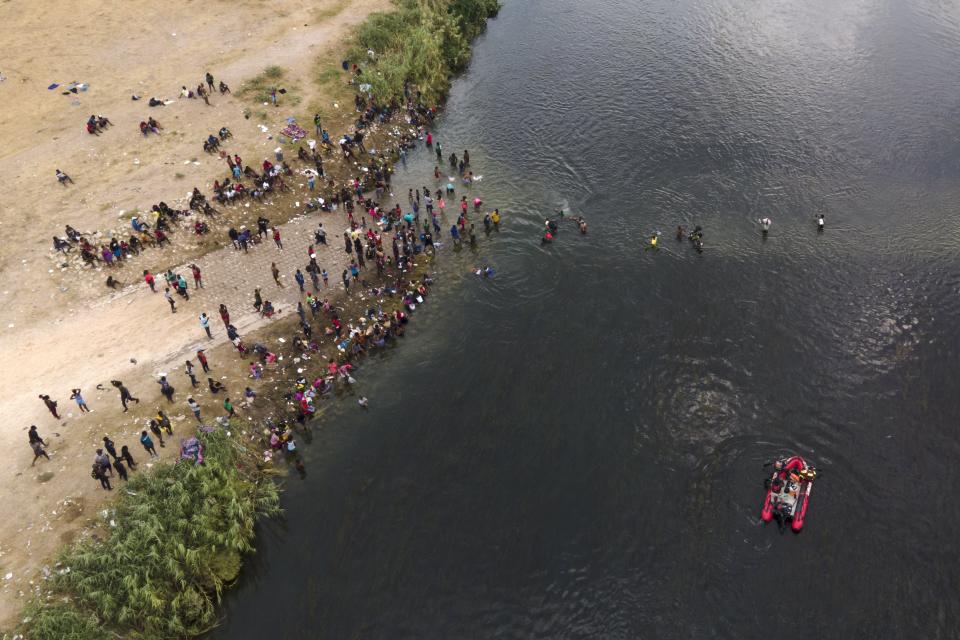 A Mexican rescue boat chugs along the Rio Grande, bottom right, as migrants, many from Haiti, wade across the river into Del Rio, Texas in 2021.