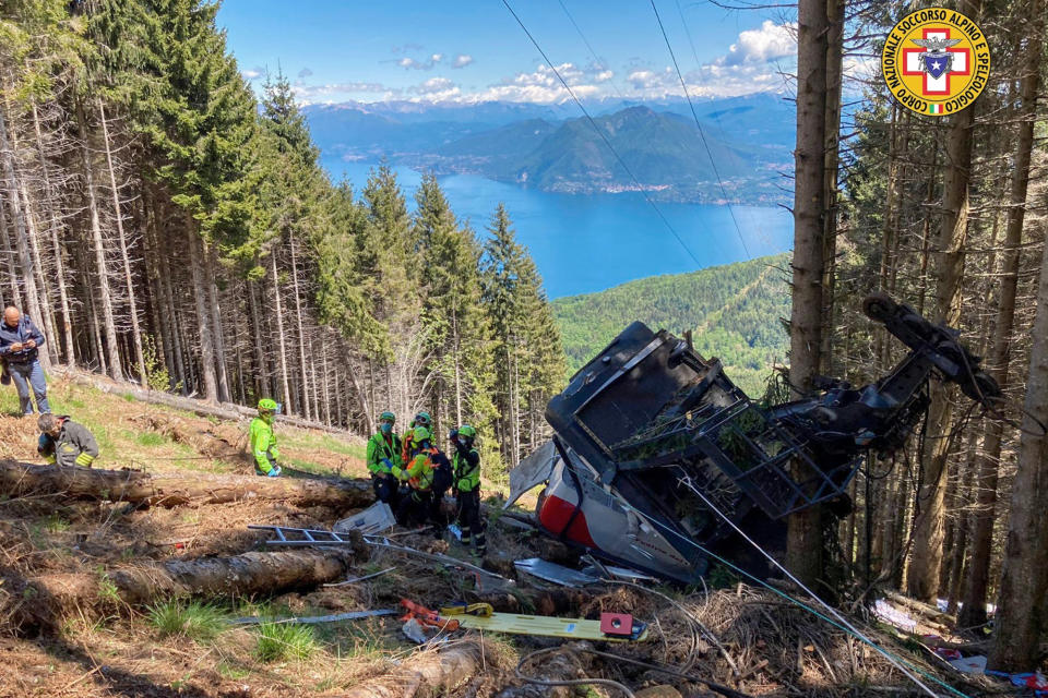 Rescuers work by the wreckage of a cable car after it collapsed near the summit of the Stresa-Mottarone line in the Piedmont region, northern Italy, Sunday, May 23, 2021. A mountaintop cable car plunged to the ground in northern Italy on Sunday, killing at least five people and sending at least three more to the hospital, authorities said. (Soccorso Alpino e Speleologico Piemontese via AP)