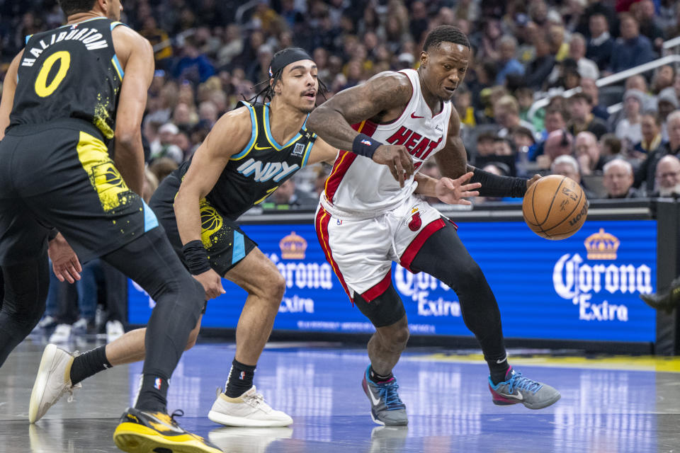 Miami Heat guard Terry Rozier, right, eludes a steal attempt by Indiana Pacers guard Andrew Nembhard, center, during the first half of an NBA basketball game in Indianapolis, Sunday, April 7, 2024. (AP Photo/Doug McSchooler)