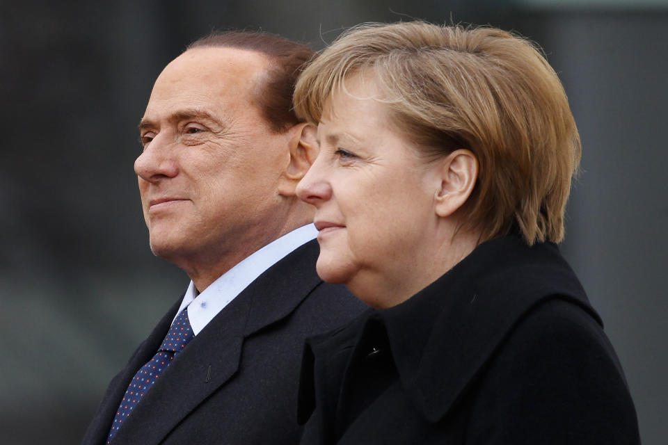 FILE - German Chancellor Angela Merkel, right, and Italian Prime Minister Silvio Berlusconi listen to the national anthems during the welcoming ceremony at the chancellery in Berlin, Germany, on Jan. 12, 2011. Berlusconi, the boastful billionaire media mogul who was Italy's longest-serving premier despite scandals over his sex-fueled parties and allegations of corruption, died, according to Italian media. He was 86. (AP Photo/Markus Schreiber, File)