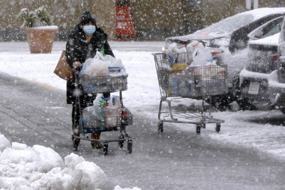 A shopper pushes a full grocery cart through heavy snow in a parking lot, Saturday, Dec. 5, 2020, in Marlborough, Mass. The northeastern United States is seeing the first big snowstorm of the season. (AP Photo/Bill Sikes)