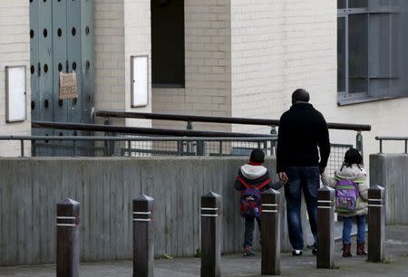 A man and his children stand in front of a closed primary and nursery school in Brussels, November 23, 2015, after security was tightened in Belgium following the fatal attacks in Paris. REUTERS/Francois Lenoir