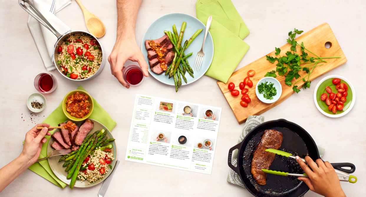 view of kitchen countertop with three hands making steak and asparagus dinner, hellofresh meal recipe kit