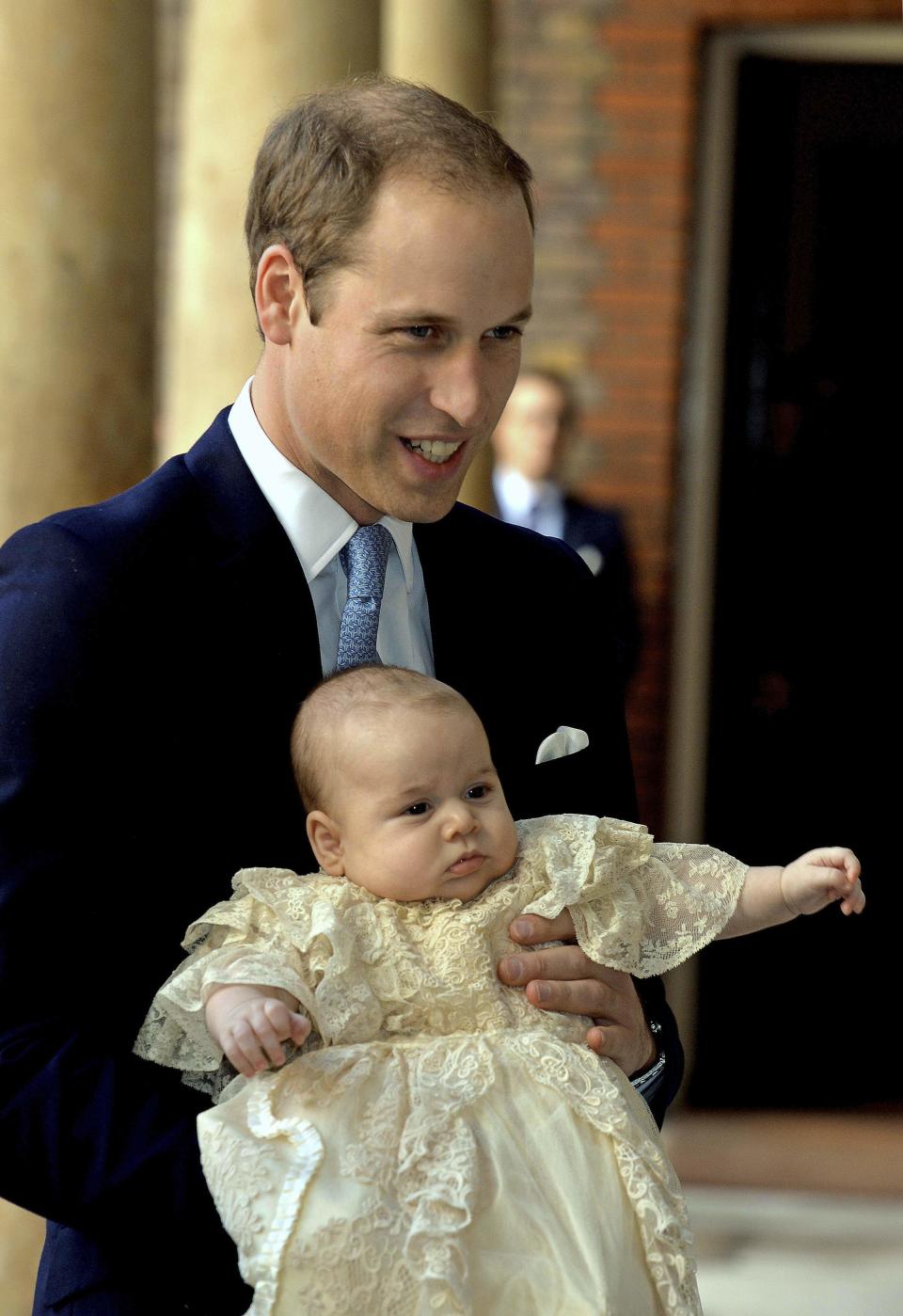 Britain's Prince William carries his son Prince George as they arrive for his son's christening at St James's Palace in London