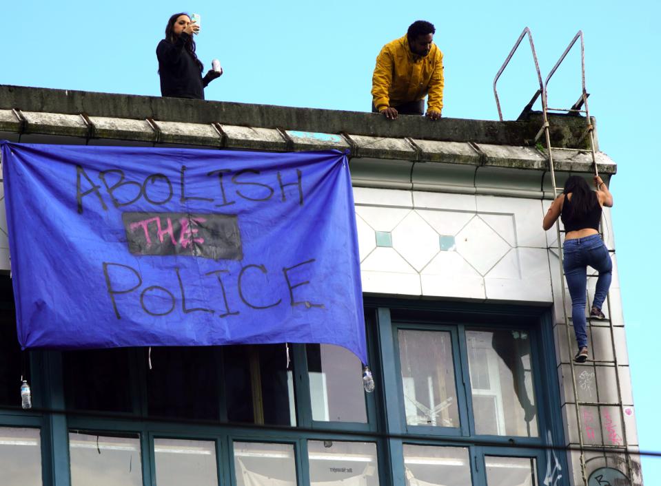A woman climbs down from a building in the Capitol Hill Autonomous Zone in Seattle during protests.