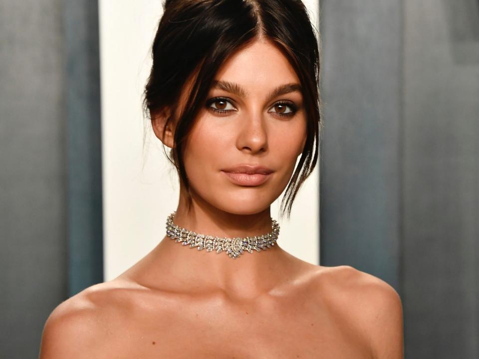 Camila Morrone, in a black strapless gown, black elbow-length gloves, and a diamond choker, poses on the red carpet at the 2020 Vanity Fair Oscars afterparty.