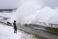 Jessica Warner watches rough surf along Lynn Shore Reservation in the aftermath of a snowstorm, Tuesday, Feb. 2, 2021, in Lynn, Mass. A sprawling, lumbering winter storm has walloped the Eastern U.S., shutting down coronavirus vaccination sites, closing schools, and halting transit. (AP Photo/Elise Amendola)