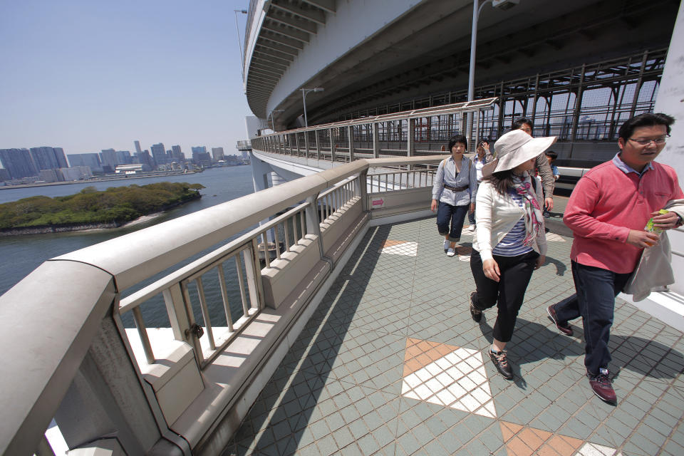 In this Sunday, May 5, 2013 photo, people walk on the walkway of the Rainbow Bridge in Tokyo. The walk is just over one mile (1.7 kilometers) including the 918-meter-long (just over half a mile) single-span suspension bridge and takes less than an hour one way. A walk on the north side of the bridge provides the panoramic view of Tokyo’s skyline. (AP Photo/Itsuo Inouye)