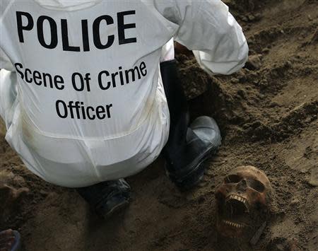 A police officer works next to a human skull at a construction site in the former war zone in Mannar, about 327 km (203 miles) from the capital Colombo, January 16, 2014. REUTERS/Dinuka Liyanawatte