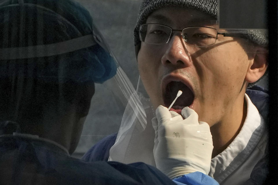 A medical worker collects a sample from a man at a coronavirus testing site in Beijing, Wednesday, Nov. 2, 2022. (AP Photo/Andy Wong)