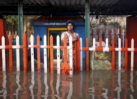 A woman stands at a fenced gate of a partially submerged temple in Chennai, India, December 4, 2015. REUTERS/Anindito Mukherjee